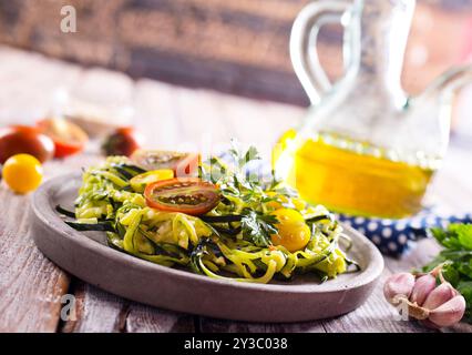 Zucchini Nudeln mit Pesto, Avocado und Tomaten auf einem grauen Teller. Rohes veganes Food-Konzept. Stockfoto