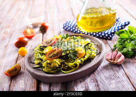 Zucchini Nudeln mit Pesto, Avocado und Tomaten auf einem grauen Teller. Rohes veganes Food-Konzept. Stockfoto