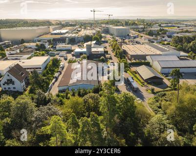 Industriegebiet mit verschiedenen Gebäuden und einem Kran im Hintergrund, Bäume entlang der Straßen, helle sonnige Atmosphäre, Industriegebiet Wolfsberg, Nag Stockfoto