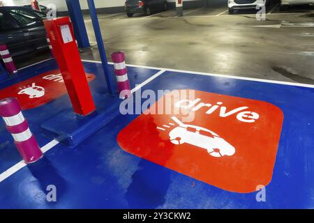 Ein Parkplatz mit einem rot-weißen Schild mit der Aufschrift Drive. Auf dem Parkplatz stehen mehrere Autos, und eine Parkuhr ist zu sehen Stockfoto