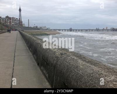 Ein Blick auf die blackpool Promenade im Winter mit stürmischem Seeturm und zentralem Pier mit nicht identifizierbaren Menschen, die entlang der Küste spazieren Stockfoto