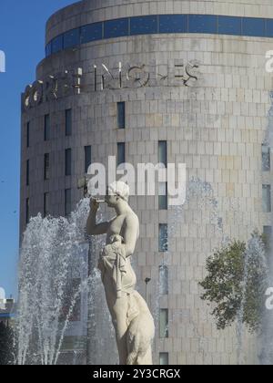 Statue neben Wasserstrahlen eines Springbrunnens vor einem modernen Gebäude bei sonnigem Wetter, barcelona, mittelmeer, spanien Stockfoto