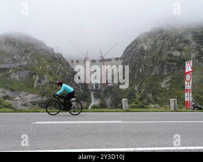 Anton Geisser 12.09.2024 Kanton Bern Schweiz. Kraftwerke Oberhasli Staumauer. Neubau Spittallam. Bild die Ersatzstaumauer im Nebel. Radfahrer auf dem Weg zum Grimsel. *** Anton Geisser 12 09 2024 Kanton Bern Schweiz Oberhasli Kraftwerke neuer Spittallam-Damm Bild des Ersatzdamms im Nebelradfahrer auf dem Weg nach Grimsel Stockfoto