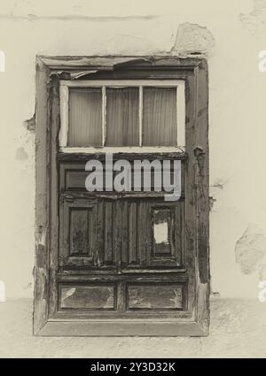 Ein Sepia-Bild eines alten spanischen Fensterverschlusses in einem traditionellen Haus mit verblassten Gipswänden bei starkem Sonnenlicht Stockfoto