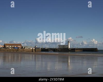 Scarborough Leuchtturm und Hafen spiegeln sich in der Sommersonne am Strand der Südbucht Stockfoto