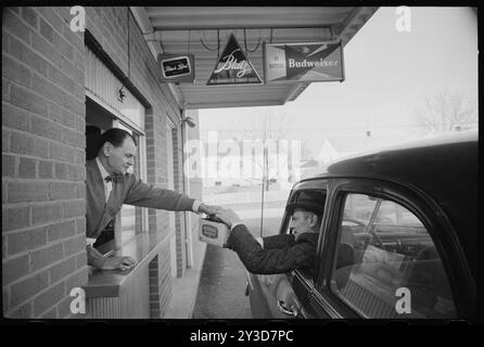 Mann in einem Drive-Thru-Fenster, der eine Schachtel nationalböhmisches Bier an Kunden in einem Auto überreicht, kein Ort, 4. Februar 1960. Foto von Marion S Trikosko/US News und World Report Magazine Foto Stockfoto