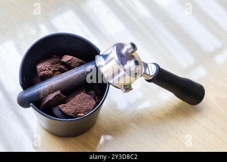 Komprimierter Kaffee, der in der Klopfbox mit Portafilter daneben gemahlen wird. Kaffeesatz sind ausgezeichnete natürliche und organische Düngemittel. Stockfoto