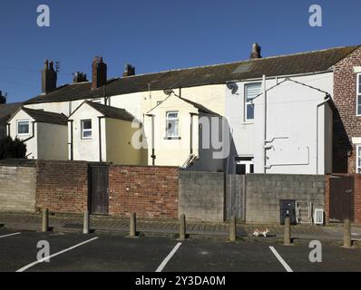 Blick auf die Rückseite einer Reihe von weiß-gelb bemalten typischen englischen Reihenhäusern mit Parkplätzen in fleetwood lancashire Stockfoto