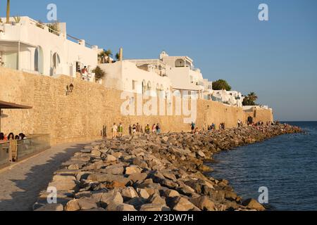 Menschen laufen zwischen dem Meer und der alten Medina von Hammamet, einem beliebten Ort bei Sonnenuntergang, in Tunesien Stockfoto