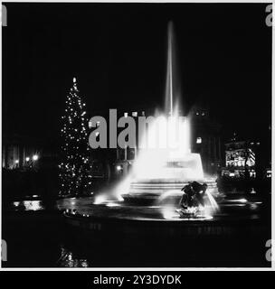 Trafalgar Square, St James, Westminster, City of Westminster, Greater London Authority, 1960-1985. Ein Brunnen am Trafalgar Square, beleuchtet bei Nacht, mit einem Weihnachtsbaum dahinter. Stockfoto