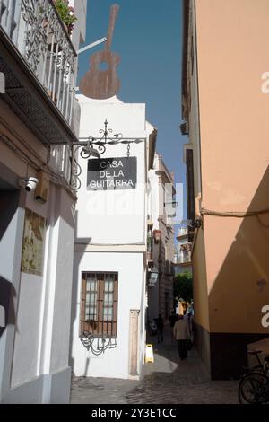 Eine der engen Gassen in der Fußgängerzone der Innenstadt, Sevilla, Spanien, 2023. Das Casa de la Guitarra (Haus der Gitarre) ist ein kulturelles Zentrum des traditionellen spanischen Flamenco. Stockfoto