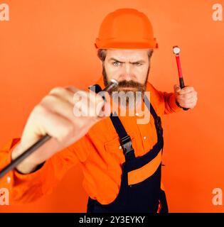 Schreinerhämmernagel. Die Arbeit des Schreiner- und Handwerkerkonzepts. Hammer und Nägel. Bärtiger Baumeister in Overalls und Huthämmernagel. Konstruktion Stockfoto