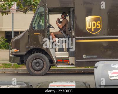 LOS ANGELES, CA - Mai 2024: UPS-Lieferwagen, der Pakete an ein Gebäude in einer Wohnstraße in West Hollywood, Kalifornien, liefert Stockfoto