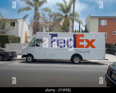 LOS ANGELES, CA - Mai 2024: FedEx-Lieferwagen, der Pakete an ein Gebäude in einer Wohnstraße in West Hollywood, Kalifornien, liefert Stockfoto