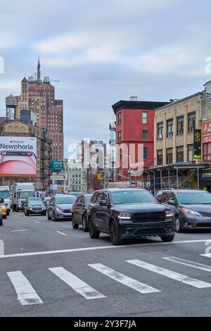New York, USA – 13. September 2024: Dieses Bild zeigt eine geschäftige Straße in Chinatown, New York, mit mehreren Fahrzeugen und einem markanten Gebäude Stockfoto
