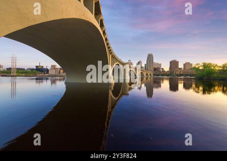 Die Skyline der Innenstadt von Minneapolis, Minnesota, USA am Mississippi River mit der Third Avenue Bridge in der Dämmerung. Stockfoto