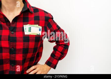 100 Euro-Banknoten in der Brusttasche eines roten karierten Hemdes. Stockfoto