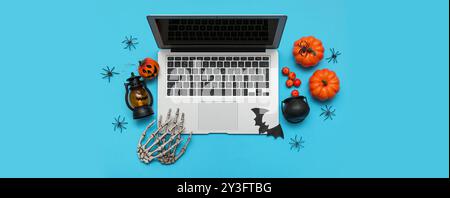 Moderner Laptop und Dekoration für Halloween auf hellblauem Hintergrund Stockfoto