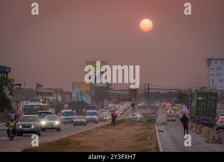 Der starke Verkehr auf den Straßen des Teshie-Viertels in Accra, Ghana, mit afrikanischen Menschen, Autos und einem wunderschönen Sonnenuntergang. Stockfoto