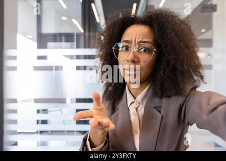 Nahaufnahme einer jungen seriösen afroamerikanischen Geschäftsfrau im Anzug, die im Büro sitzt und Videokonferenzen und Online-Meetings abhält, die Probleme aufgebracht und frustriert löst. Stockfoto