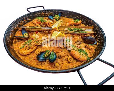 Das traditionelle spanische Meeresfrüchte-Gericht Paella in einer schwarzen Pfanne mit Muscheln und Garnelen auf einem Reisblock - isoliert auf weiß Stockfoto