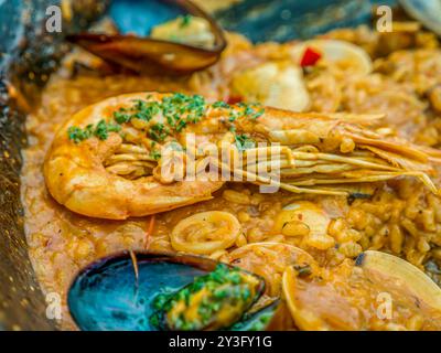 Das traditionelle spanische Meeresfrüchte-Gericht Paella in einer schwarzen Pfanne mit Muscheln und Garnelen auf einem Reisblock Stockfoto