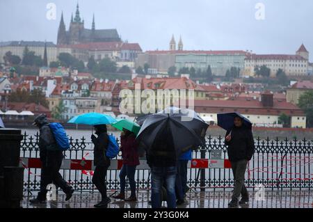 Prag, Tschechische Republik. September 2024. Menschen laufen am 13. September 2024 im Regen in der Nähe der Moldau in Prag, Tschechien. Die Tschechische Republik bereitet sich auf mögliche größere Überschwemmungen vor, nachdem Meteorologen in den nächsten Tagen eine extreme Hochwasserwarnung auf den größten Teil des Landes ausgeweitet haben. Quelle: Dana Kesnerova/Xinhua/Alamy Live News Stockfoto