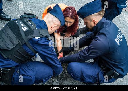 Ein Polizist entfernt den Klebstoff, der die Hand des Klimaaktivisten während der Kundgebung auf der Straße klebt. Aktivisten der Umweltaktionsgruppe „Letzte Generation“ (Ostatnie Pokolenie) blockierten den Fahrzeugzugang zum polnischen parlament in Warschau. In orangefarbenen Westen klebten die Aktivisten ihre Hände an die Straße und trugen Banner, die verkündeten, dass die Regierung ihre Zukunft stehle. Die Aktion soll das Bewusstsein für die Klimakrise durch Störungen schärfen und ist eine von vielen, die sich für billigere und umfassendere öffentliche Verkehrsmittel einsetzen sollen. Die Gruppe fordert, dass die Regierung wechselt Stockfoto