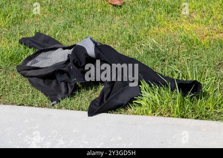 Schwarze und graue Jacke liegt auf dem Gras Stockfoto