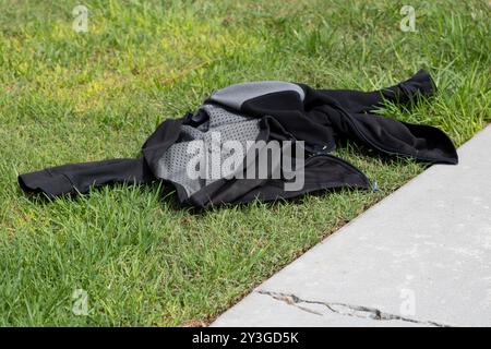 Schwarze und graue Jacke liegt auf dem Gras Stockfoto