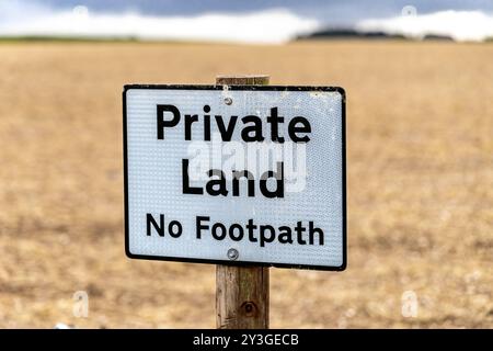 Flacher Fokus eines privaten Weges ohne Fußweg am Rande eines landwirtschaftlichen Ackerfeldes Stockfoto