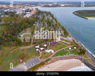 Aus der Vogelperspektive sehen Sie eine Skate-Bowl und einen Caravan Park entlang eines breiten Flusses, der in Port Macquarie in New South Wales, Au, fließt Stockfoto