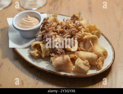 Eine Portion gebratener Tintenfisch mit Knoblauchsoße in einem europäischen Restaurant Stockfoto