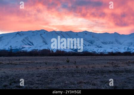 Pulsierender Sonnenuntergang über der schneebedeckten Bergkette in der Nähe von Twizel Stockfoto