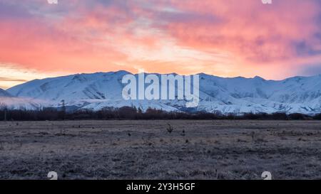Pulsierender Sonnenuntergang über der schneebedeckten Bergkette in der Nähe von Twizel Stockfoto