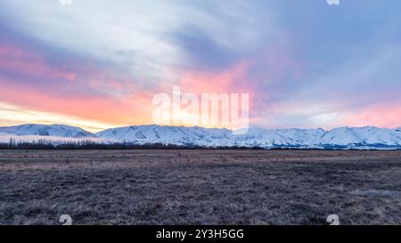 Pulsierender Sonnenuntergang über der schneebedeckten Bergkette in der Nähe von Twizel Stockfoto