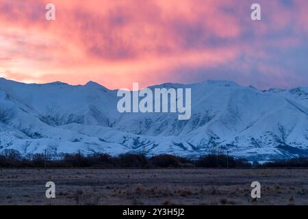 Pulsierender Sonnenuntergang über der schneebedeckten Bergkette in der Nähe von Twizel Stockfoto
