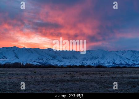 Pulsierender Sonnenuntergang über der schneebedeckten Bergkette in der Nähe von Twizel Stockfoto