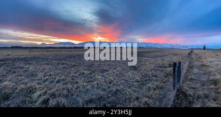 Pulsierender Sonnenuntergang über der schneebedeckten Bergkette in der Nähe von Twizel Stockfoto