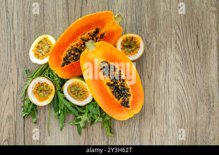 Papaya-Frucht, Passionsfrucht und Rucola auf hellem hölzernem Hintergrund. Scheiben süßer Papaya und Maracuja auf hölzernem Hintergrund, halbe Papayas, Kopie Stockfoto