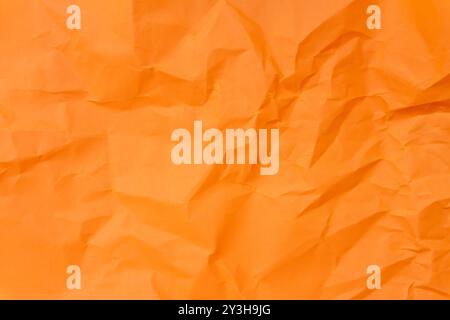 Die Ansicht von oben und der ganze Rahmen von zerknittertem oder zerknittertem orangefarbenem Papier wird als zerknitterte Papierhintergrundstruktur bei dekorativen Kunstwerken verwendet. Stockfoto