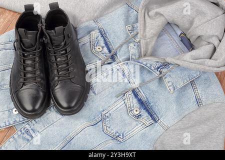 Kleidung, Schuhe und Accessoires - Top View Closeup Jeans Kapuzenjacke und Winterfellstiefel auf hölzernem Hintergrund Stockfoto