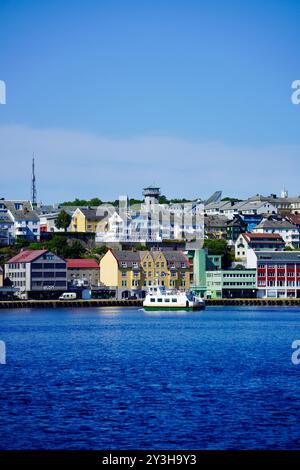 Ein malerischer Blick auf den Hafen von Torshavn auf den Färöer Inseln mit farbenfrohen Gebäuden und einem Boot an einem klaren, sonnigen Tag. Stockfoto