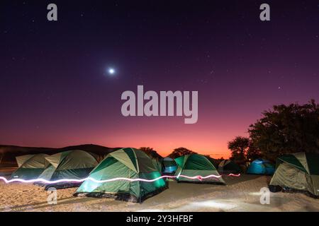 Ein Vollmond erleuchtete diese Szene am frühen Morgen einer Gruppe von Zelten auf einem Campingplatz im Süden Namibias. Stockfoto