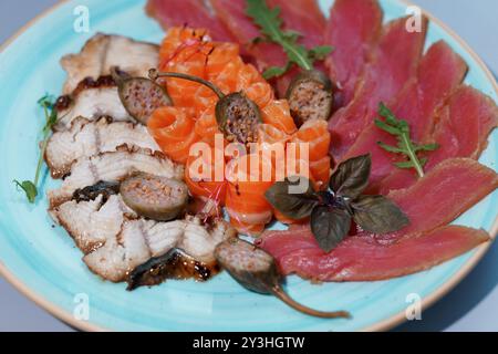 Exquisite Gourmet-Platte mit verschiedenen Sushi und Sashimi, kunstvoll präsentiert auf eleganter blauer Platte. Stockfoto