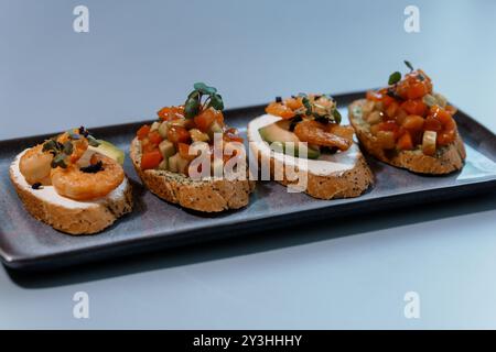 Exquisites Gourmet-Bruschetta-Sortiment mit Garnelen und frischem Gemüse auf handwerklichem Brot. Stockfoto