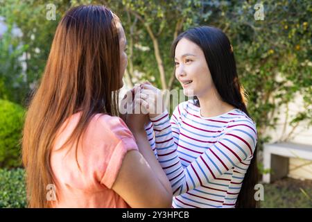 Hände halten, asiatische Mutter und Tochter knüpfen und lächeln im Garten Stockfoto