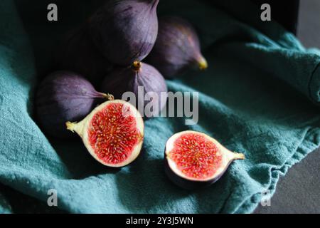 Nahaufnahme frischer reifer Feigenfrüchte in grünem Stoff mit dunklen Schatten Stockfoto