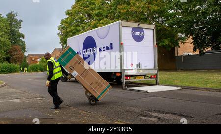 Milton Keynes, UK - 3. September 2024: Currys Lieferarbeiter in einer Hi-Vis-Weste, liefert einen neuen Kühlschrank, in einer Pappschachtel, auf einem Dolly zu einem britischen Zuhause Stockfoto