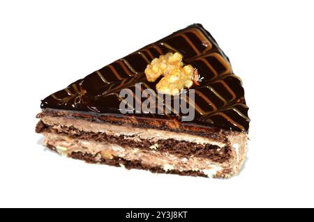 Dreieckiges Schokoladenkuchenstück gefüllt und garniert mit Walnuss, Schichten Schokoladenpaste Creme und Stücken, mit Schichten Schlagsahne, serviert Stockfoto